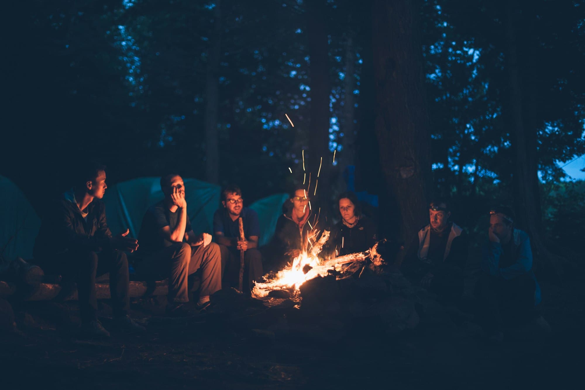 Friends gathered around a campfire at dusk