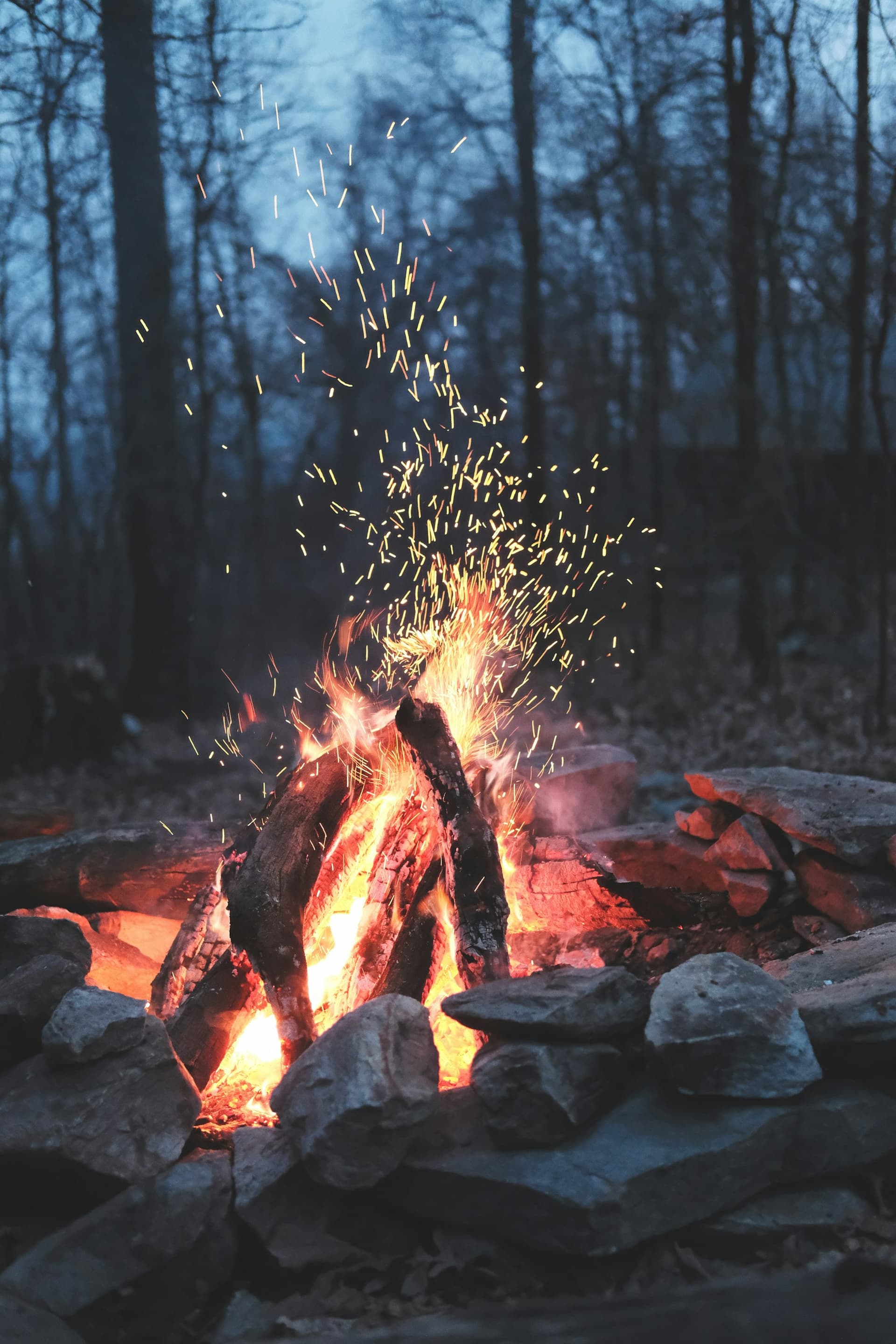 A campfire throwing sparks into the dusk