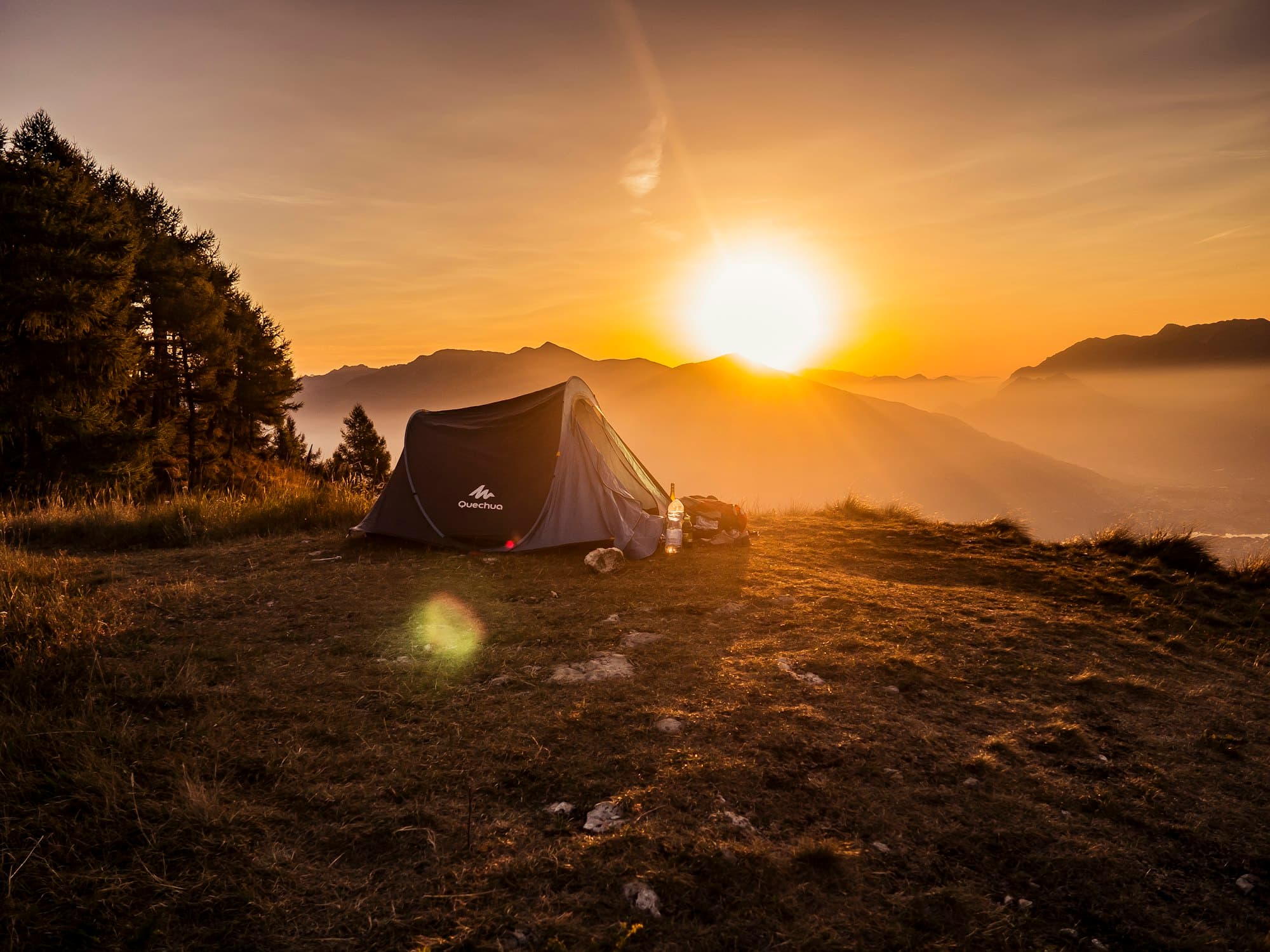A tent pitched on a mountain ridge at golden sunset